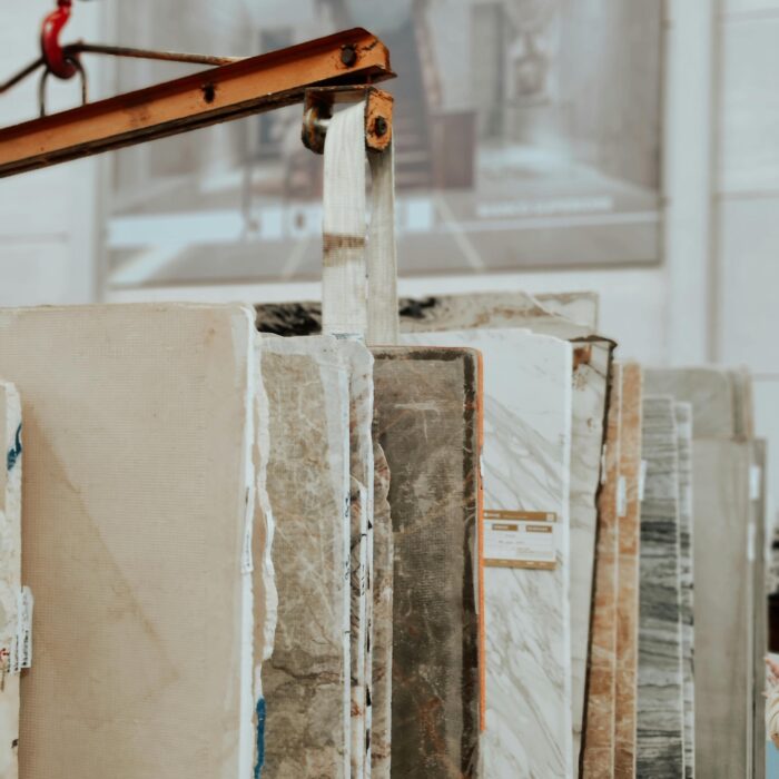 Vertical shot of marble and granite slabs with a construction hook indoors.